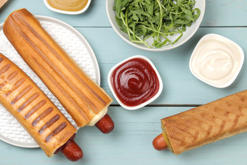 French hot dogs. Delicious hot dogs and mustard, mayonnaise, ketchup on a light blue wooden table. fast food street food. sausages in a bun. top view