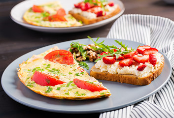 Omelette with tomatoes, ham and green onion on dark table.  Frittata - italian omelet.