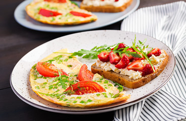 Omelette with tomatoes, ham and green onion on dark table.  Frittata - italian omelet.