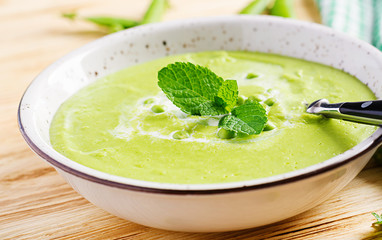 Green pea soup in bowl on wooden table. French cuisine.