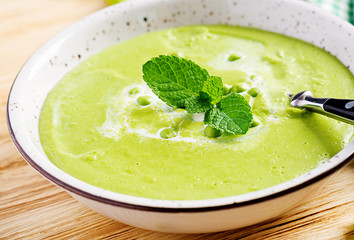 Green pea soup in bowl on wooden table. French cuisine.