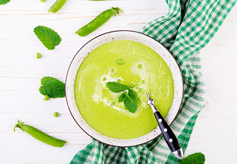 Green pea soup in bowl on wooden table. French cuisine. Top view