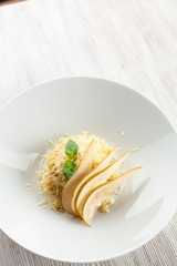 Traditional italian risotto with creamy sauce and grated cheese, decorated with sliced ripe pear and basil on a white rustic background