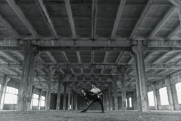 A young girl and boy perform acrobatic moves in the premises of an old factory, a warehouse, acro 