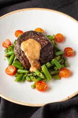 Medium rare mignon fillet roasted with green beans and fresh cherry tomatoes, decorated with creamy sauce for a healthy dinner in a restaurant