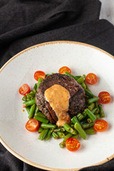 Medium rare mignon fillet roasted with green beans and fresh cherry tomatoes, decorated with creamy sauce for a healthy dinner in a restaurant