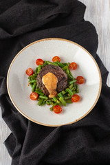 Medium rare mignon fillet roasted with green beans and fresh cherry tomatoes, decorated with creamy sauce for a healthy dinner in a restaurant
