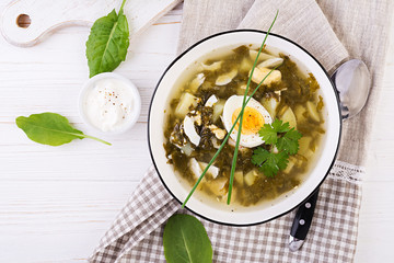 Green soup of sorrel in white bowl. Flat lay. Top view