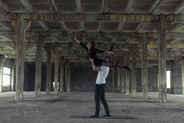 A young girl and boy perform acrobatic moves in the premises of an old factory, a warehouse, acro 