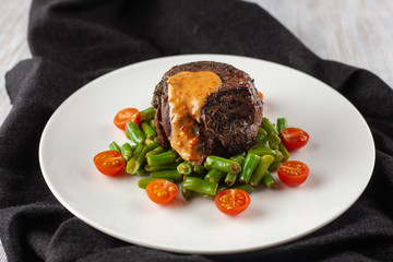 Medium rare mignon fillet roasted with green beans and fresh cherry tomatoes, decorated with creamy sauce for a healthy dinner in a restaurant