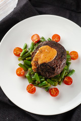 Medium rare mignon fillet roasted with green beans and fresh cherry tomatoes, decorated with creamy sauce for a healthy dinner in a restaurant