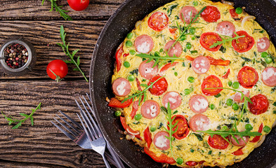 Omelette with tomatoes, sausage and green peas  in rustic style.  Frittata - italian omelet. Top view