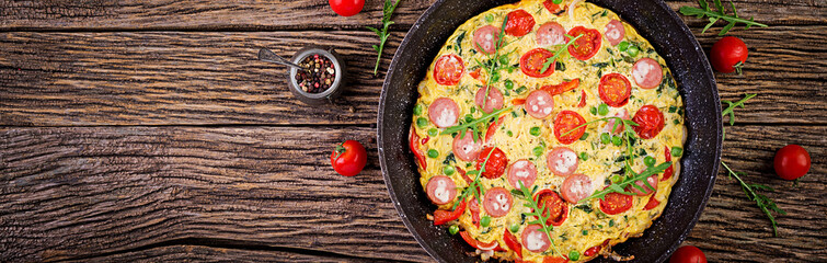 Omelette with tomatoes, sausage and green peas  in rustic style.  Frittata - italian omelet. Banner. Top view