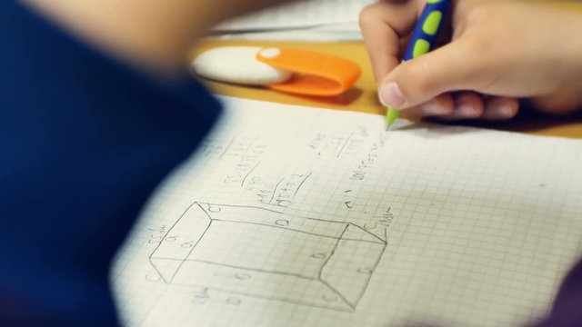 Young boy doing his hard school homework while sitting at desk