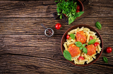 Fusilli  pasta with meatballs in tomato sauce and basil in bowl. Italian cuisine. Top view. Flat lay