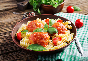 Fusilli  pasta with meatballs in tomato sauce and basil in bowl. Italian cuisine.
