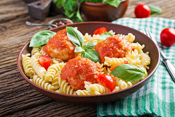 Fusilli  pasta with meatballs in tomato sauce and basil in bowl. Italian cuisine.