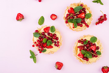 Tarts with strawberries, currant and whipped cream decorated with mint leaves. Top view