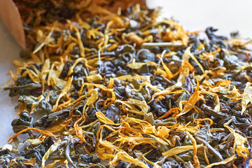 Herbal tea closeup. Multi coloured dried herbal tea leaves and brown kraft paper bag with selective focus.  