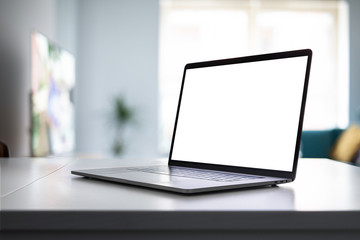 Laptop blank screen on the table in home interior - angle view