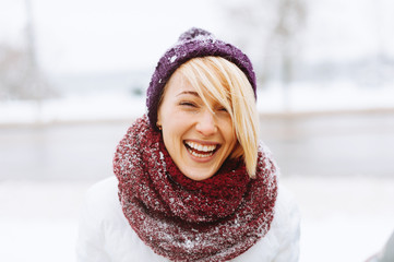 A young woman is laughing outside, in winter.