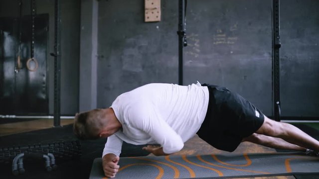 High performance triathlon or marathon exercises. Man in good fit does right side plank wraps for improving sports training. Available exercises for office workers. Intermediate no equipment exersize
