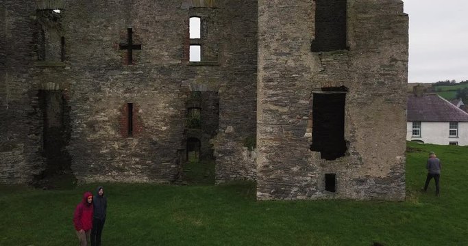 Caislean Rath Bhoth (Raphoe Castle, Bishops Palace), Slow Aerial pullback revealing ancient structure with tourists walking around grounds
