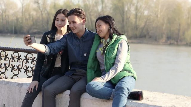 Three beautiful Asian teenagers taking a funny selfie with their smartphone. School friends having a good time together.