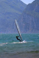 Young woman windsurfing at Lake Garda glistening in the sun (Torbole, Italy)