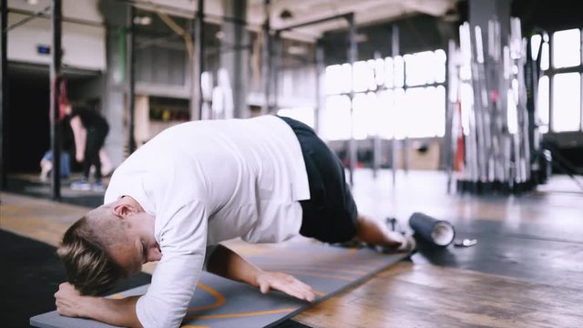 High performance triathlon or marathon exercises. Man in good fit does left side plank wraps for improving sports training. Available exercises for office workers. Intermediate no equipment exersize