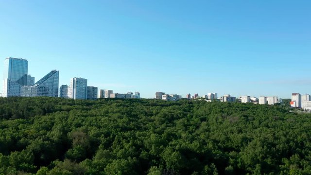 Green city in Russia.Camera flies over the forest and approach buildings in the dormitory area. Part 1