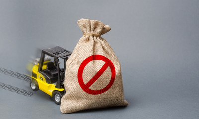 Yellow forklift truck can not lift the bag with the symbol NO. Economic pressure and sanctions. trade wars, stagnation. Restriction on the importation of goods, proprietary for business.