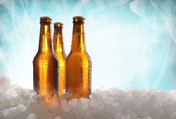 Three full beer bottles on ice and blue background