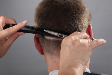 Close-up, master hairdresser does hairstyle with scissors and comb