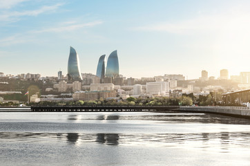Fototapeta na wymiar Baku city at sunset. Panoramic view of the skyline with sea boulevard, pier and Flame towers in the background. The capital city of Azerbaijan in summer.