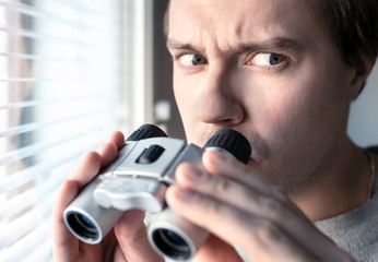 Suspicious, skeptic and confused man with binoculars. Conspiracy theory, paranoia, skepticism or...