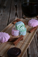 Sweets (Turkish Delight, Marshmallow, Biscuit) in close-up on a wooden table.