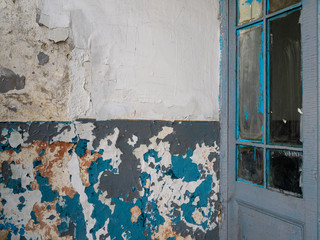 Old door and peeling wall. Many layers of paint on the wall of the old house