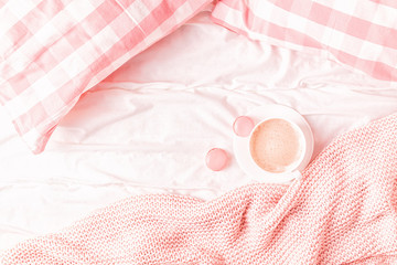 Obraz na płótnie Canvas Bed with pink knitted plaid, coffee and macaroons.