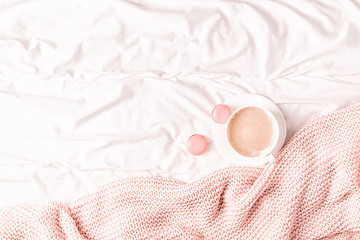 Fototapeta na wymiar Bed with pink knitted plaid, coffee and macaroons.