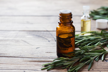 Rosemary essential oil in a glass bottle with fresh branch rosemary herb on wooden table for spa,aromatherapy and bodycare.Copy space.