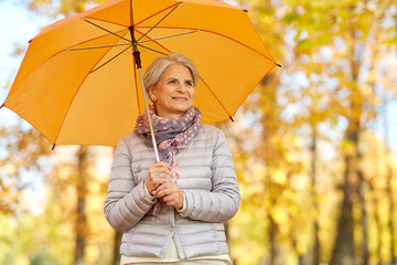 old age, weather and season concept - portrait of happy senior woman with umbrella at autumn park