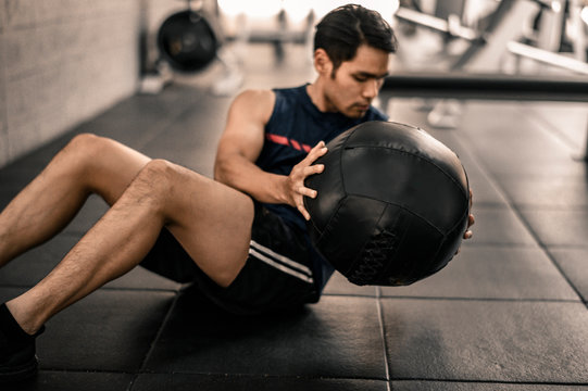 Man doing crunch with ball at the gym
