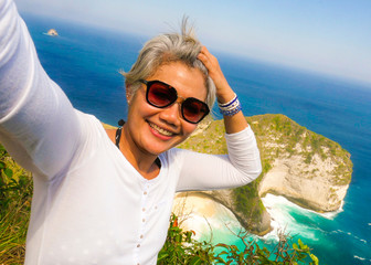 middle age 50s happy and cheerful Asian woman with grey hair taking selfie with mobile phone at...