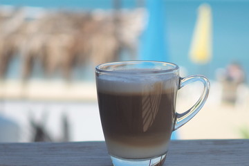 Hot coffee on a wooden table, sea view.