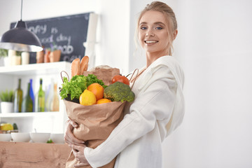 Young woman holding grocery shopping bag with vegetables Standi