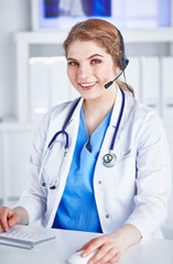 Portrait of a happy smiling young doctor in headset in office