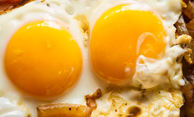 Close-up of two yellow soft fried eggs on roasted onions, bachelor meal