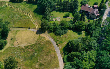 Aerial view of a meadow area with a few houses and a loose stock of bushes and trees.