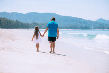 Father and his little daughter with long hair walking at beach. Family vacation. Travel concept